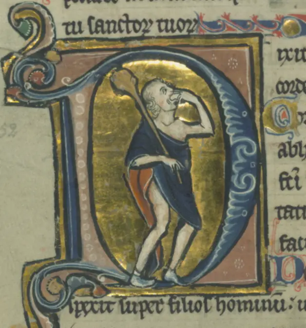 A medieval illuminated initial D containing a fool with a club, biting into a loaf of bread